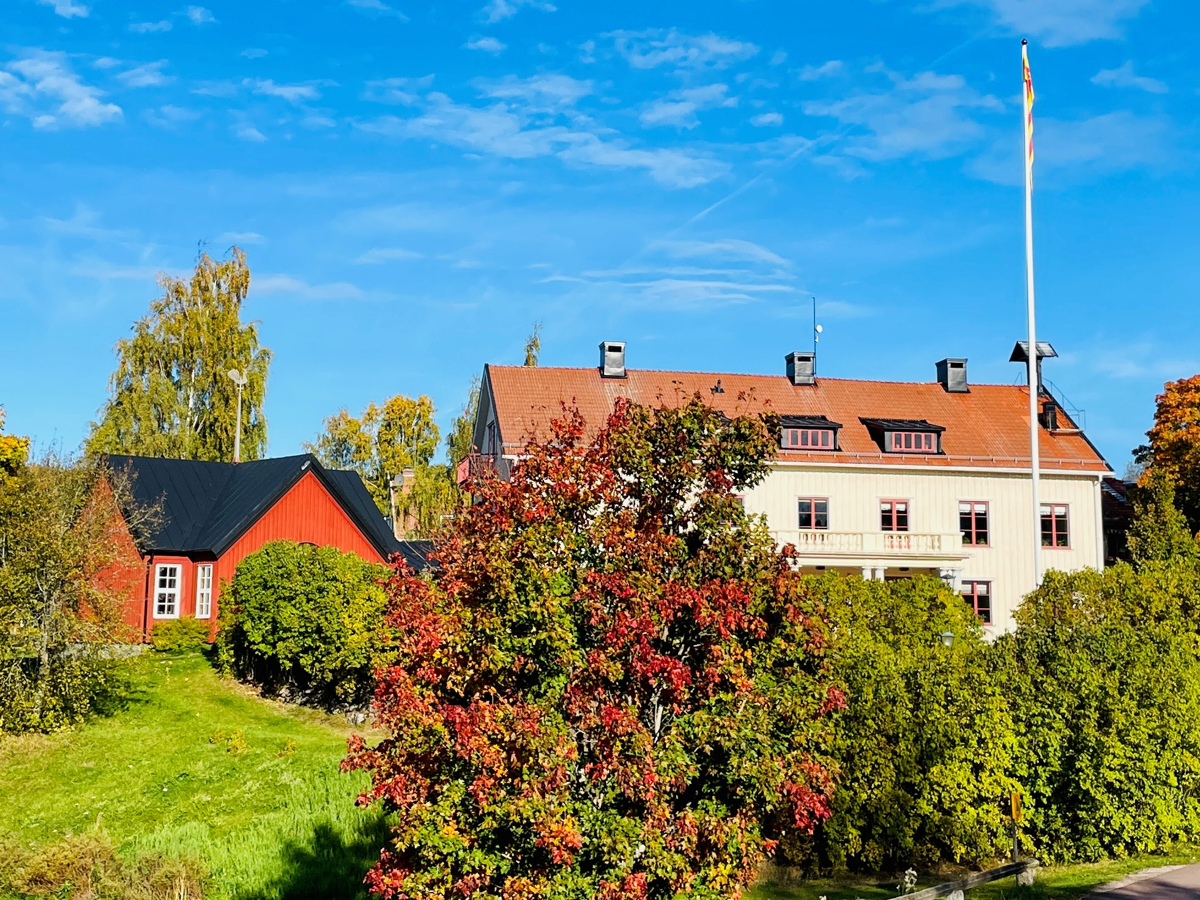 Ett rutt och vitt hus omgivna av träd med höstfärger.