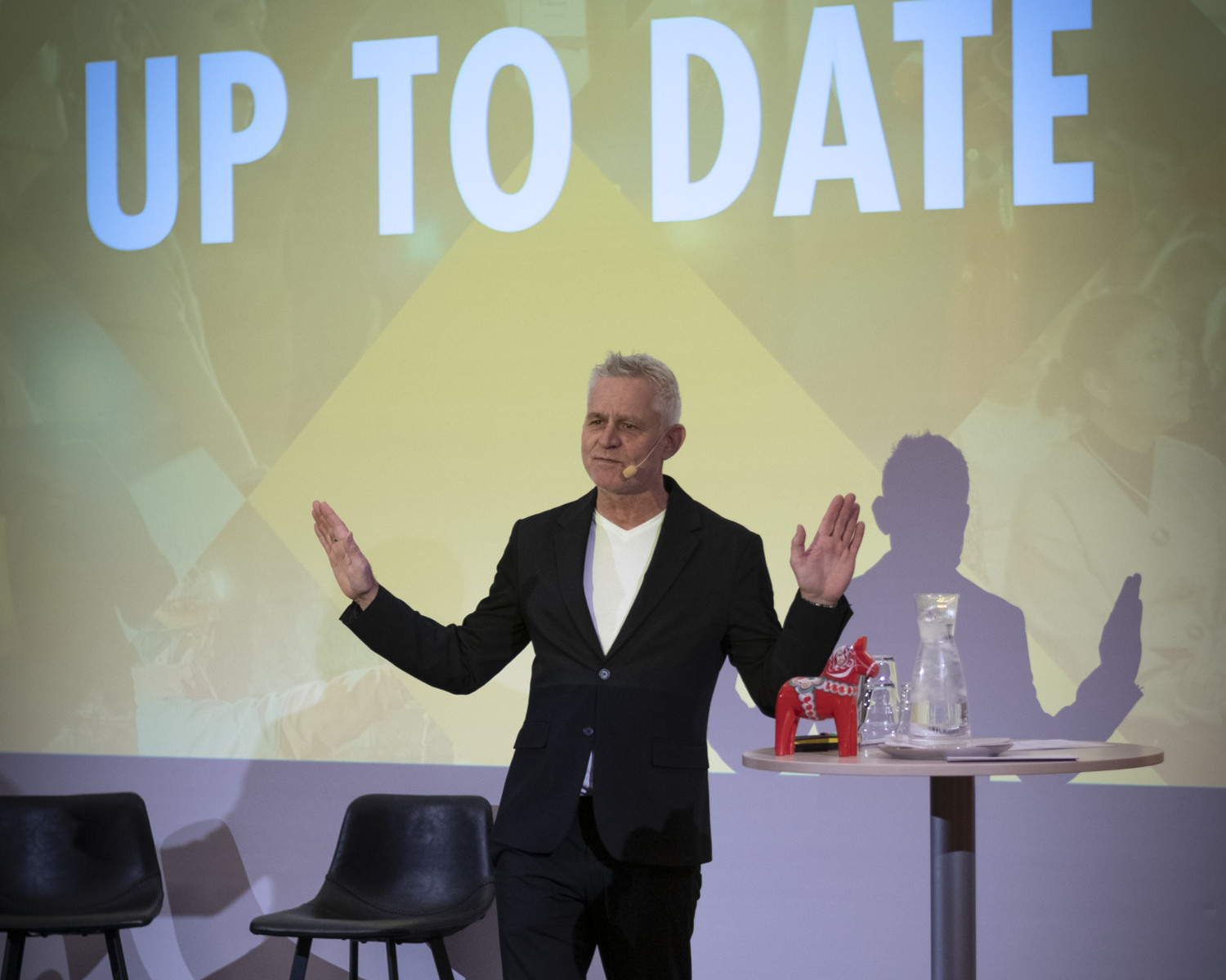 En man står på en scen och presenterar.