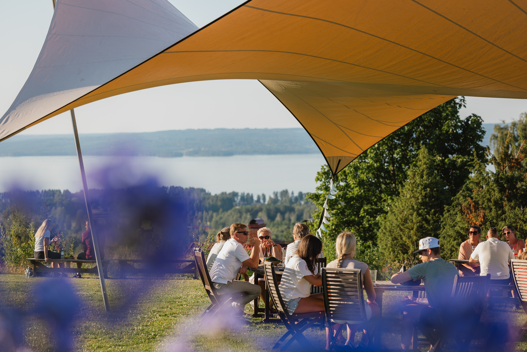 En uteservering med utsikt över en sjö som är full med folk sommartid.
