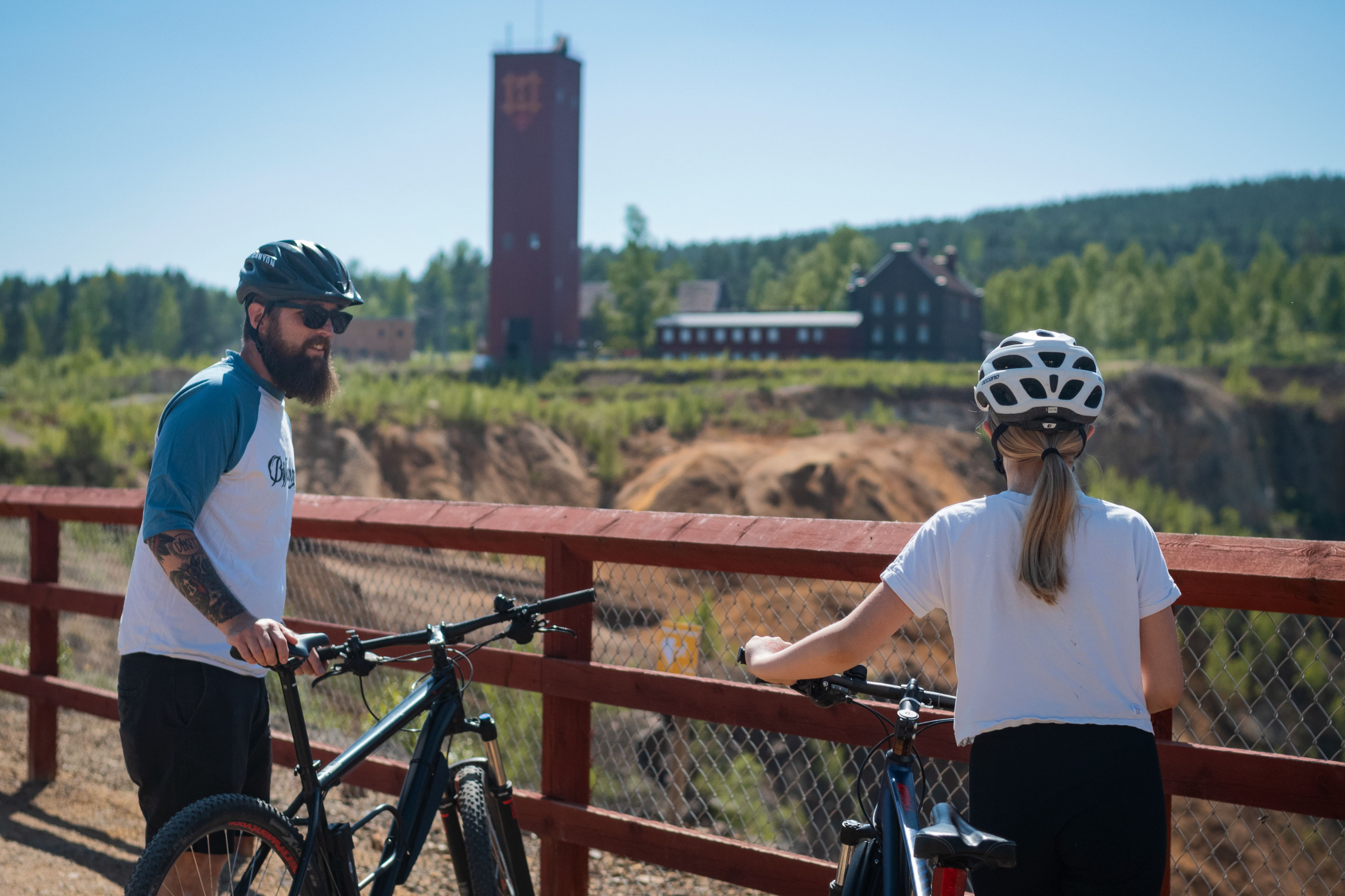 Två personer står med cyklar intill en gruva.