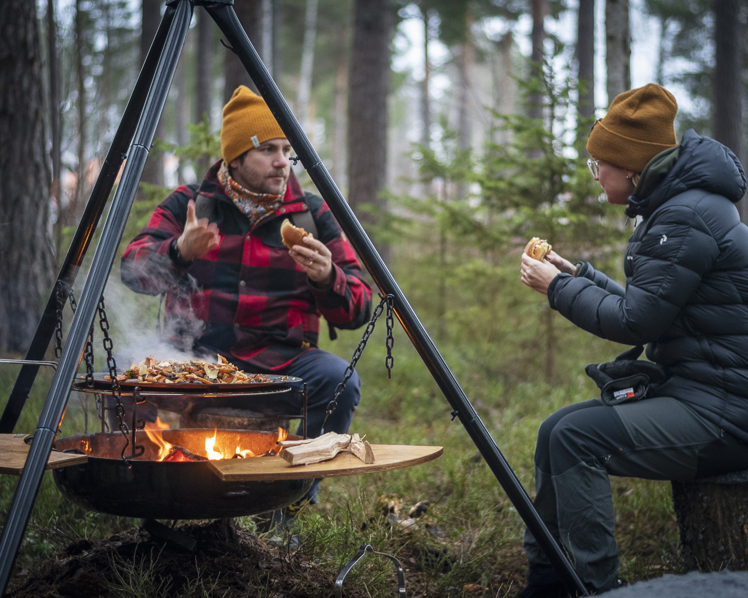 Två personer sitter vid en eld utomhus.