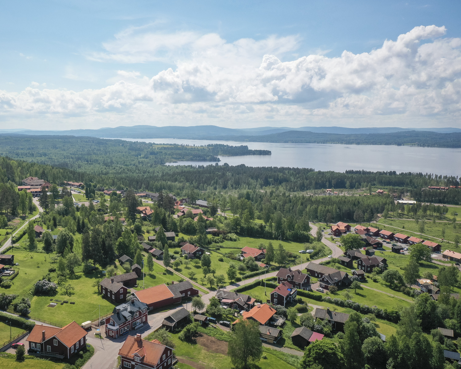 utsikt över byn Tällberg, sjön Siljan och blå berg från drönare