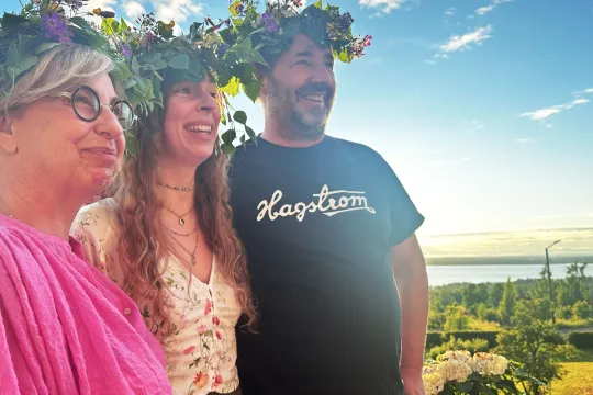 Tre människor med blomsterkransar i håret.