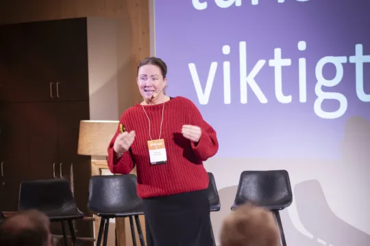 Kvinna står på scen och håller föredrag.