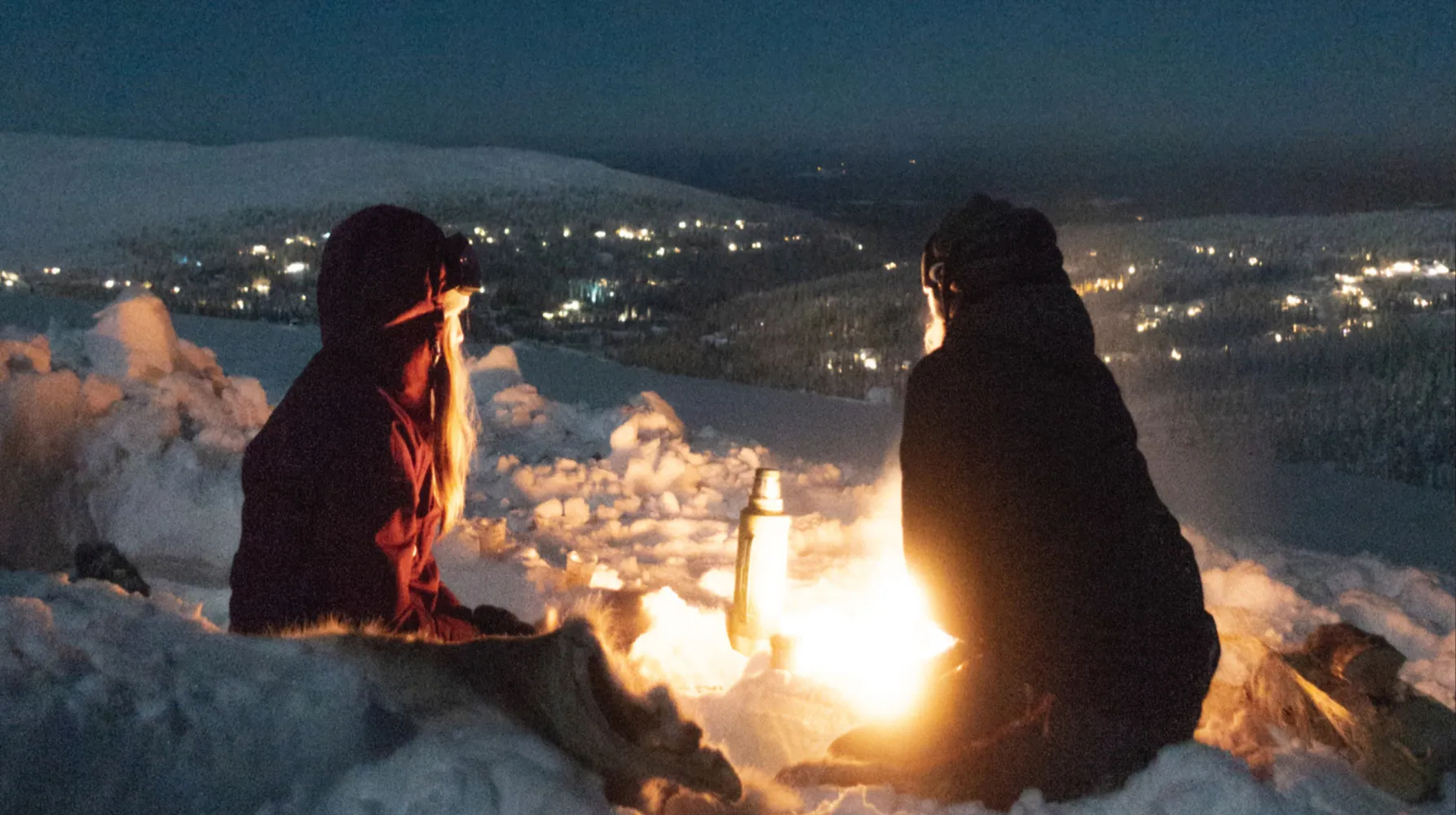 Två personer i snön en kväll.