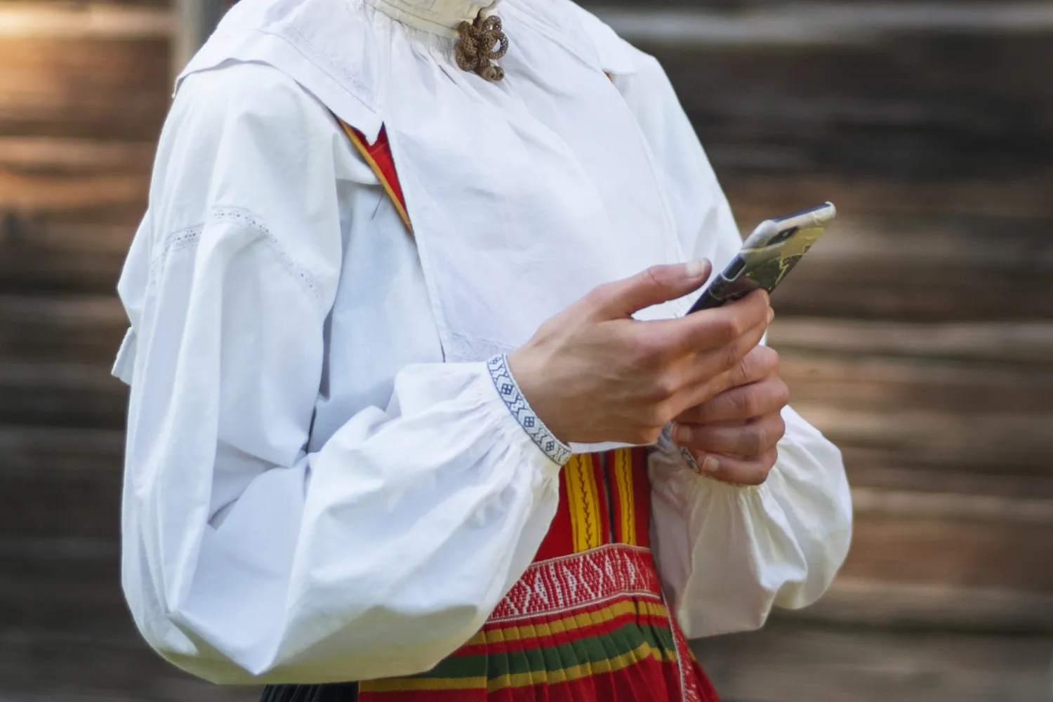 Tjej med folkdräkt håller i en mobil.