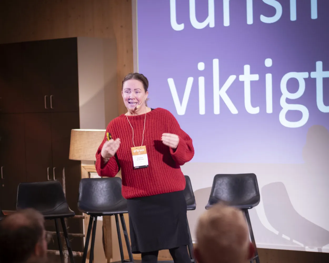 Kvinna står på scen och håller föredrag.