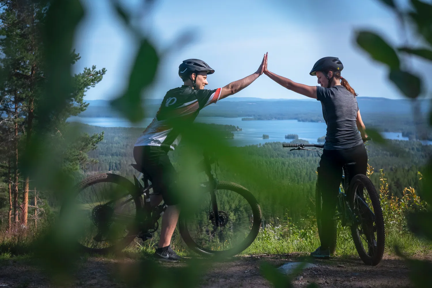 Två cyklister gör high five längs en Biking Dalarna-led i Bjursås.
