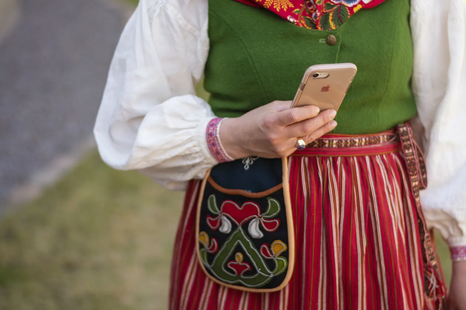 Kvinna i folkdräkt håller i mobiltelefon.