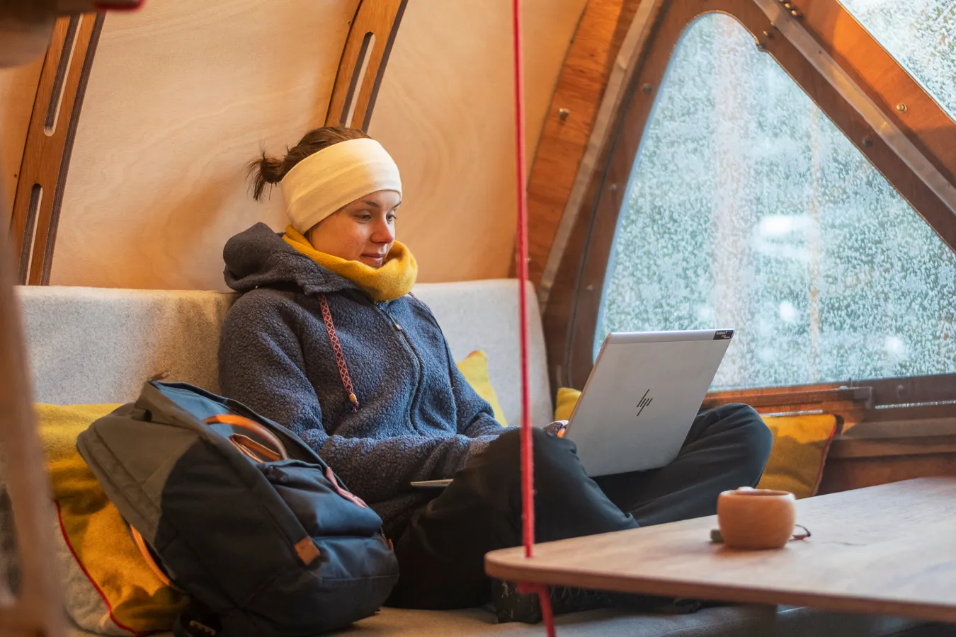 Kvinna sitter i skräddarställning med laptop i knät.