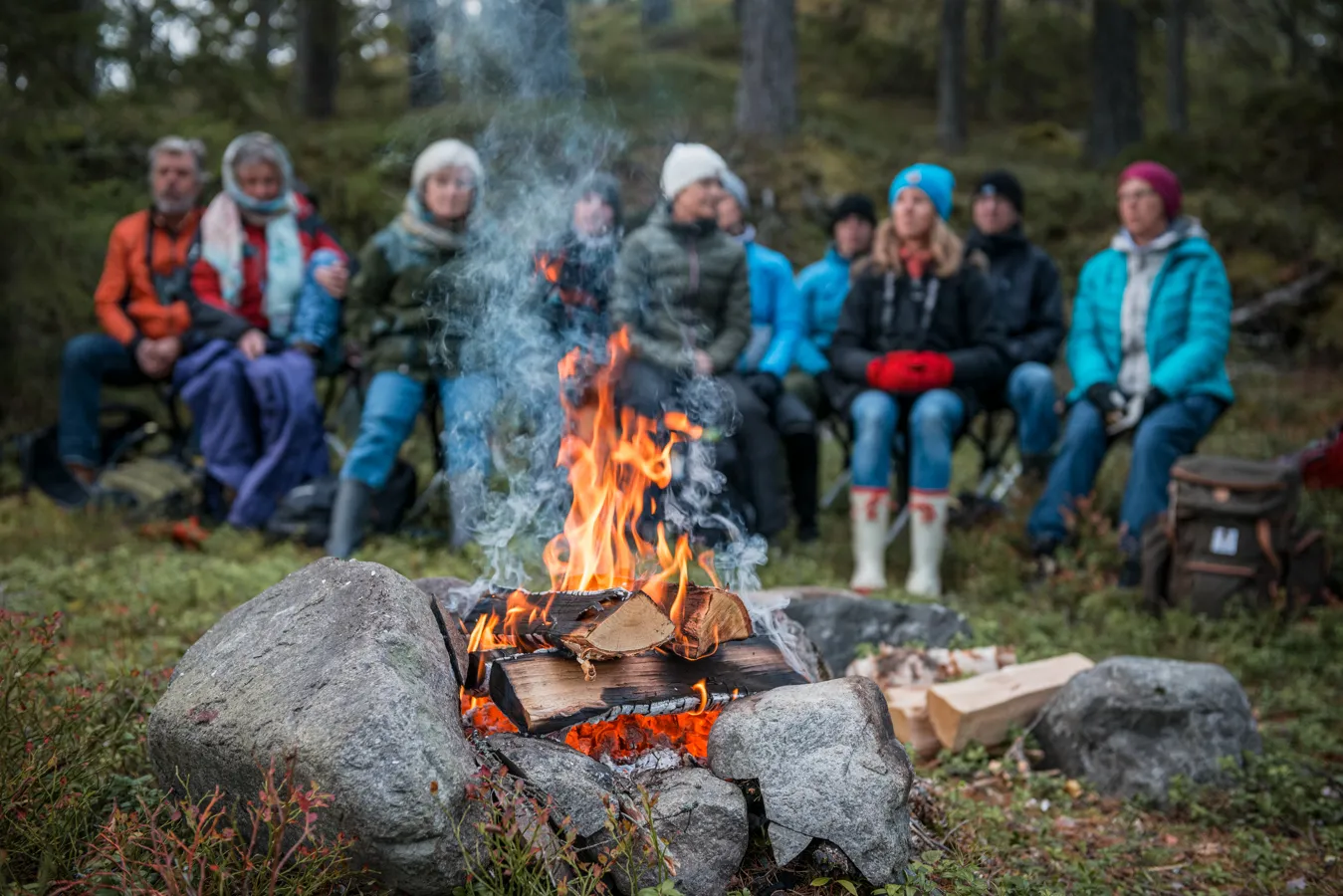 En grupp människor sitter intill en lägereld.