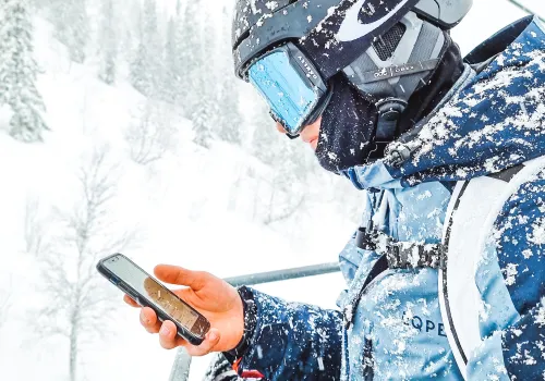 Person i skidlift och håller i en mobil.