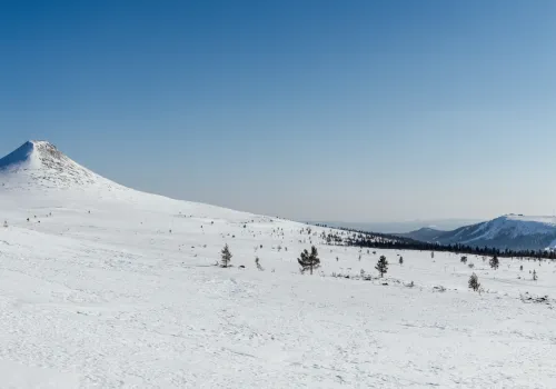 Snötäckt soligt vinterlandskap med utsikt över berg i norra Dalarna.