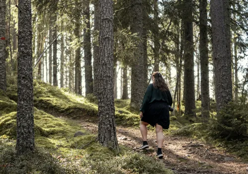 En kvinna går på en skogsstig.