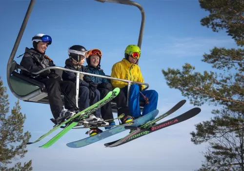 Fyra personer sitter i skidlift vintertid.