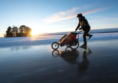 En person åker skridskor med vagn på sjö.