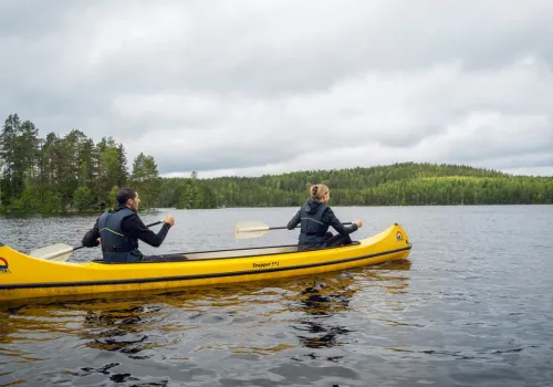 Två personer paddlar kanot sommartid.