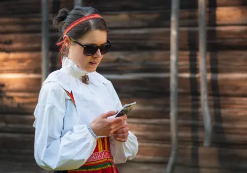 Kvinna klädd i folkdräkt tittar på mobil.