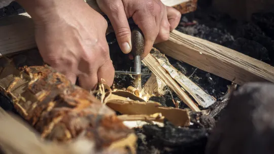 Någon tänder en brasa med tändstål.