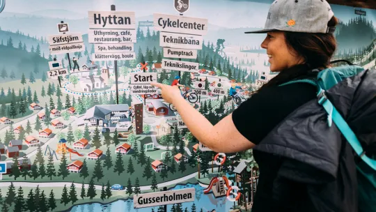 Kvinna pekar på en skylt med en stor karta.