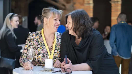 Två kvinnor som pratar vid ett bord.