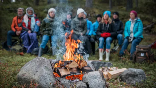 En grupp människor sitter intill en lägereld.