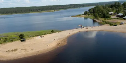 A beach surrounded with trees and a small bridge 