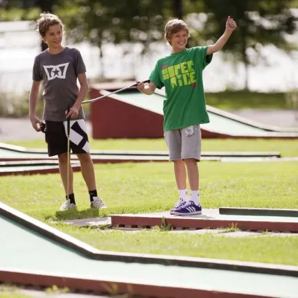 Tvo children playing miniature golf.