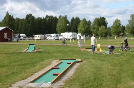 People playing on the golf course with caravans in the background.