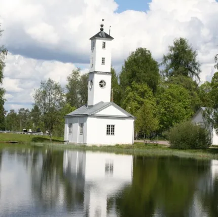 Vit kyrka intill damm.
