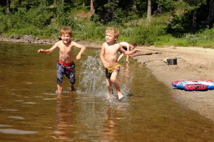 Two kids running in the water and bathtoys on the beach