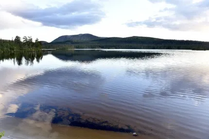 Stora Harundsjön blänker med fjäll i bakgrunden.