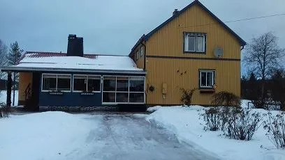 The outside of a yellow house on a winter day.