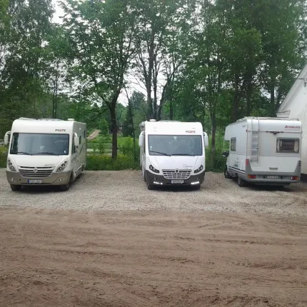 Tre husbilar på en grusplan.