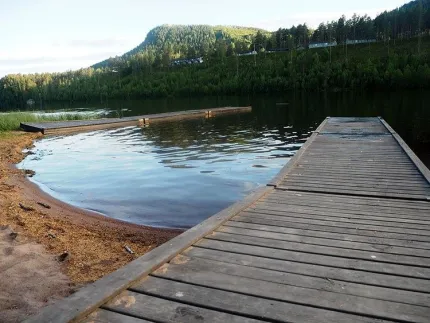 En sjö med två bryggor och träd och berg i bakrgrunden