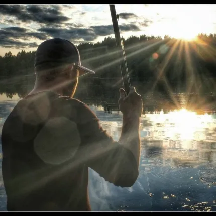 Fiskare med solnedgång som blänker i vattnet.