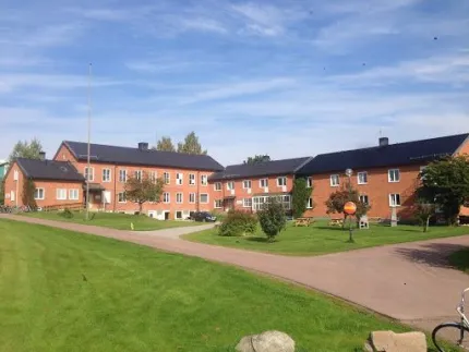 Exteriör av tvåvåningsbyggnad med gröna gräsmattor utanför.