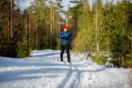 En kvinna åker skidor i spåret en solig dag.
