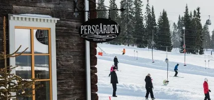 Huset Persgården från utsidan med i snö och människor i backen.