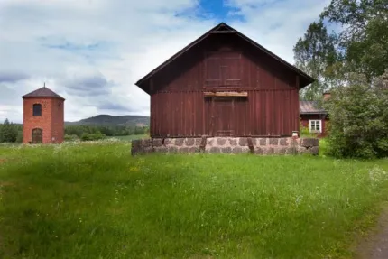 Rött hus och hytta i sommarlandskap.