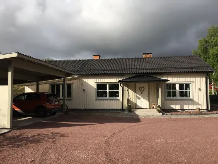 Vitt enplanshus med dubbel carport vid sidan om entrén. 