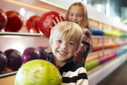 Pojke och flicka med bowlingklot i famnen.